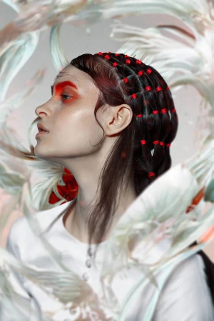 Profile of woman with red eyeshadow and beads in hair against an abstract floral background in a beauty and fashion setting.