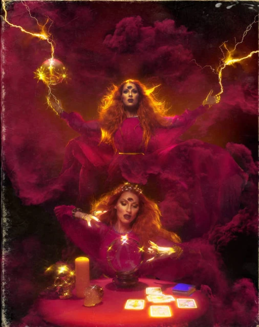 Two women in red dresses and elaborate headpieces are featured, one seated at a table with tarot cards, the other holding a glowing orb.