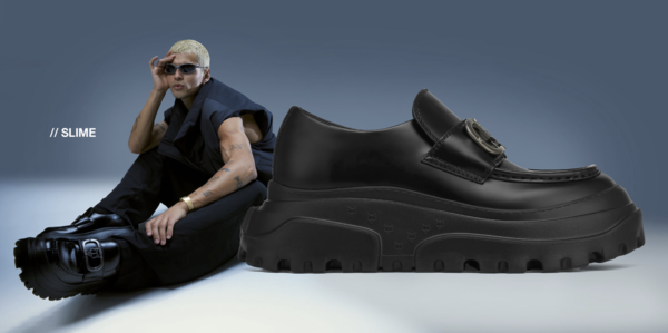 Elevated fashion shoe product shot: Black lug-soled loafer alongside a model in matching monochrome attire and black sunglasses.