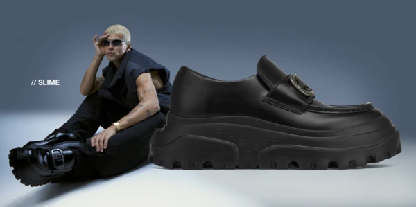 Elevated fashion shoe product shot: Black lug-soled loafer alongside a model in matching monochrome attire and black sunglasses.