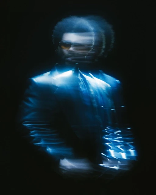 Portrait of male adult with sunglasses, wearing a suit, captured with intentional blur and a dark background, blue color cast.