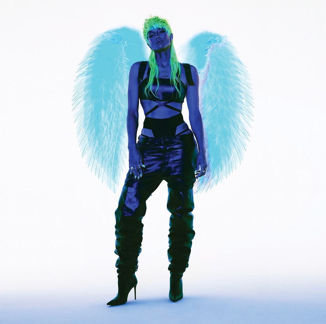 Full-length shot of woman with green hair, dark outfit, wings, and high heels against a white background. Fashion and beauty shot.