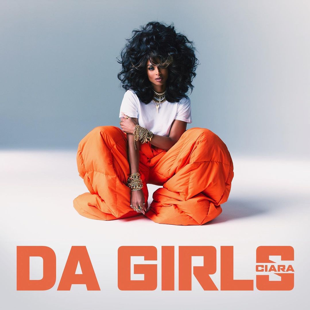 Ciara poses sitting in orange puffy pants with big hair and bracelets in a bright photo studio for the single DA GIRLS.