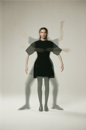 Model in black dress with multiple ghosted motion blur exposures against a neutral light grey background