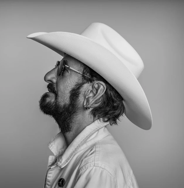 Black and white side profile of an adult man wearing a cowboy hat and eyeglasses, with facial hair and a buttoned shirt.