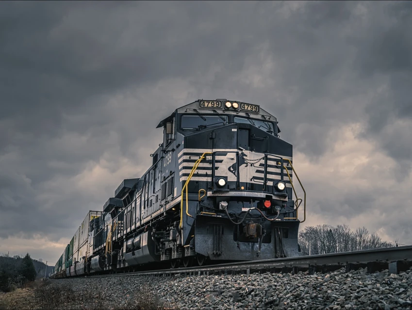 A black and silver locomotive train with the number 4799 travels on tracks under a cloudy sky, providing a powerful industrial image.
