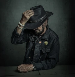 Portrait of Ringo Starr wearing a dark denim jacket and a black fedora hat, photographed by Dan Winters.