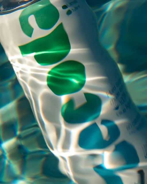 A soda can submerged in a swimming pool with light refracting off the water and creating a visually interesting effect.