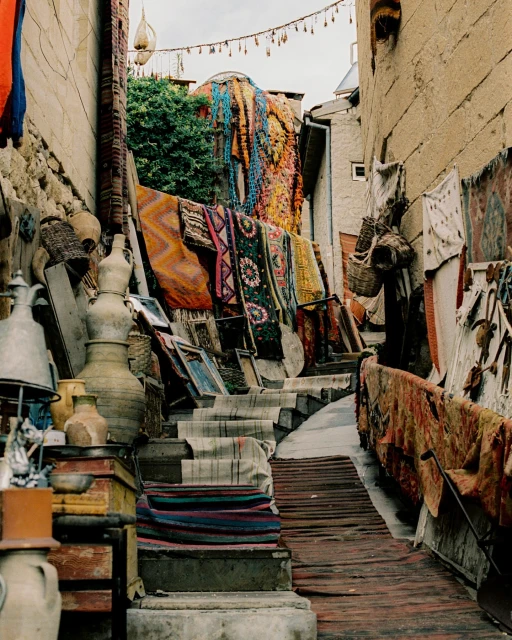 Outdoor marketplace scene with a staircase lined with rugs and decorative objects, creating a vibrant, textured display in an urban setting.