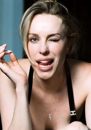 Close-up portrait of a woman winking and smiling with her tongue slightly out, wearing a black strap top and delicate pendant necklace.