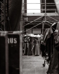 Group of musicians in traditional charro suits with wide-brimmed hats standing backstage among staging equipment