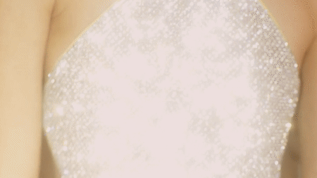 Close-up portrait of a person wearing a glittering silver sequin halter top with a reflective sparkling texture.