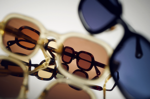 Close-up of layered tortoiseshell and dark sunglasses stacked against a white background