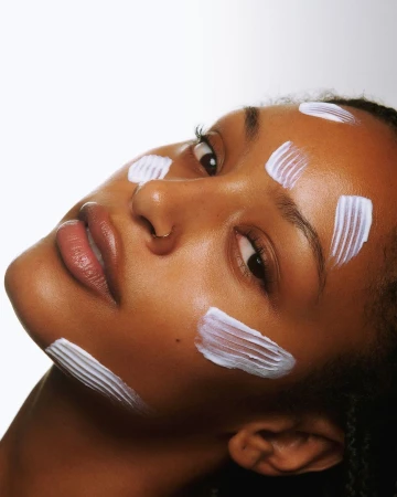 Close-up beauty portrait of a black woman with white cream swatches on her face, photographed by Laviena & Echev in Los Angeles.