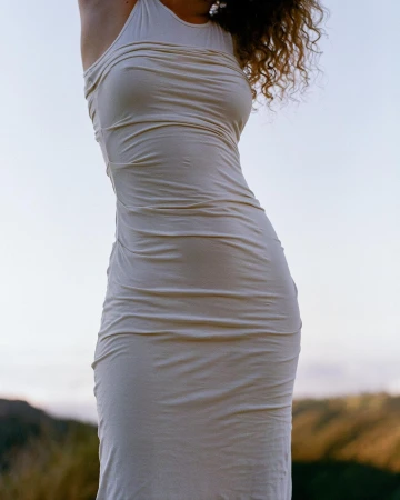 Close-up portrait of a woman wearing a cream halter neck dress outdoors against a distant natural horizon background