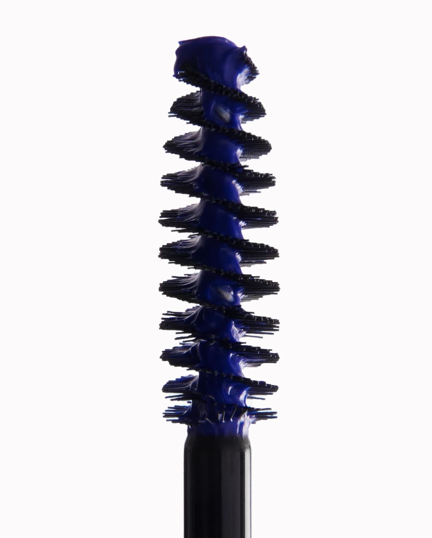 Close-up of a blue mascara brush applicator against a clean white background, beauty product shot for cosmetic advertising and marketing.