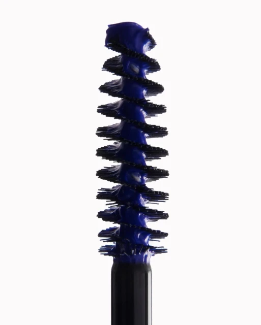 Close-up of a blue mascara brush applicator against a clean white background, beauty product shot for cosmetic advertising and marketing.