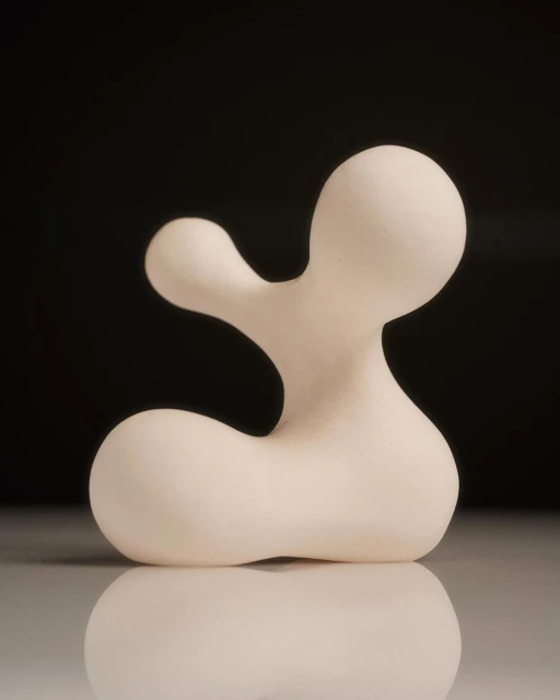 Abstract white sculpture with smooth, rounded forms against a dark background, reflecting on a glossy surface.
