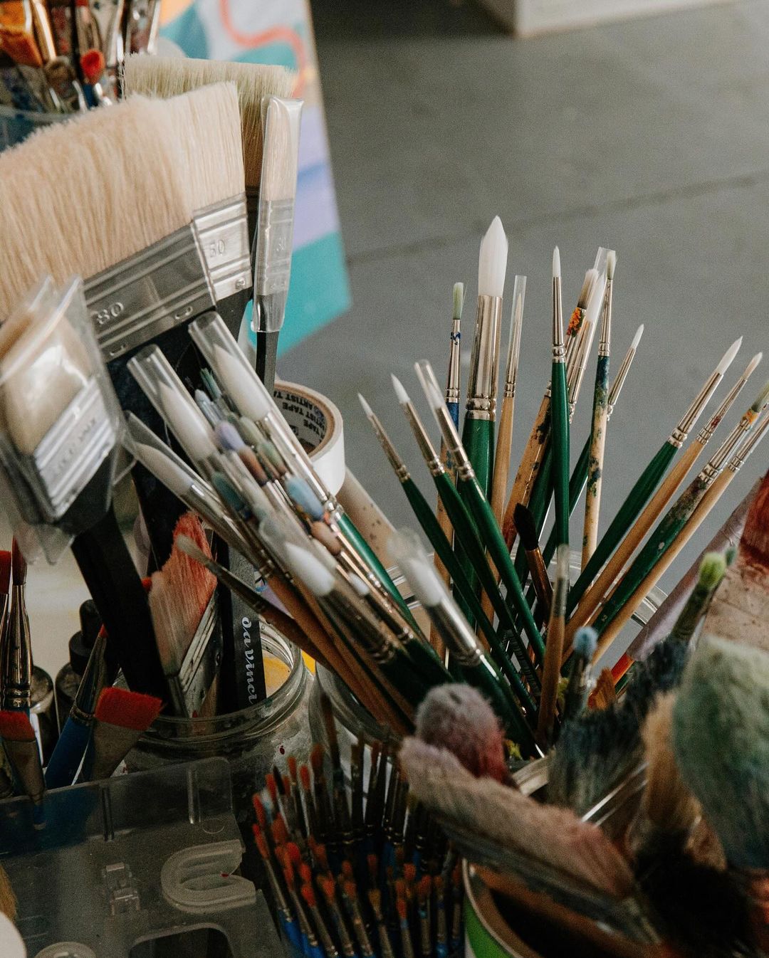 Close-up of assorted paintbrushes in containers, arranged in an art studio, providing a detailed look at the tools of the artist.