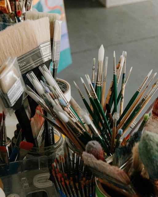 Close-up of assorted paintbrushes in containers, arranged in an art studio, providing a detailed look at the tools of the artist.