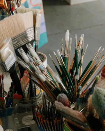 Close-up of assorted paintbrushes in containers, arranged in an art studio, providing a detailed look at the tools of the artist.
