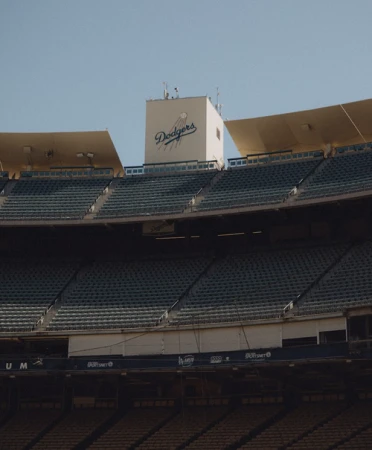 View of Dodger Stadium featuring empty green seats and the Dodgers logo set against a clear blue sky, capturing a quiet moment.