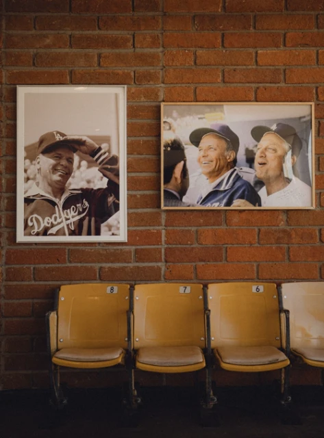Interior brick wall with framed photos of Dodgers players and yellow stadium chairs. A nostalgic nod to baseball history.