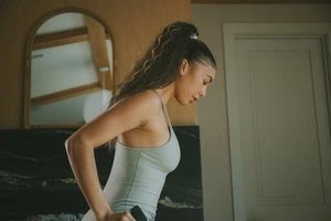 Woman in grey athletic wear working out in a room with a mirror and wooden door