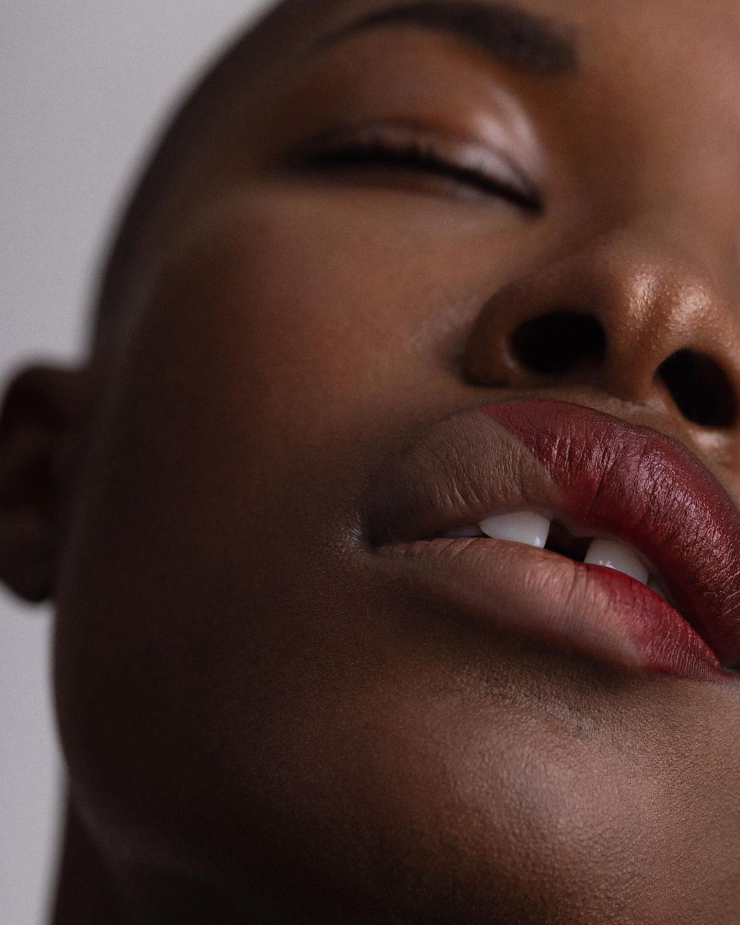 Extreme close-up beauty portrait of a Black woman with closed eyes showing dual-toned lipstick by photographer Angela Marklew.
