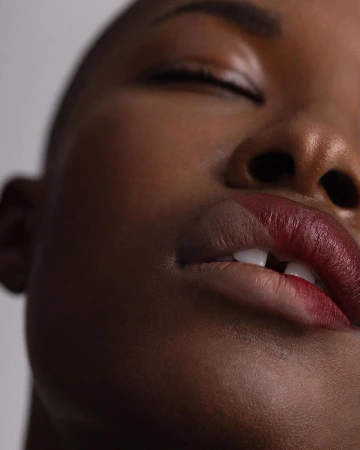 Extreme close-up beauty portrait of a Black woman with closed eyes showing dual-toned lipstick by photographer Angela Marklew.