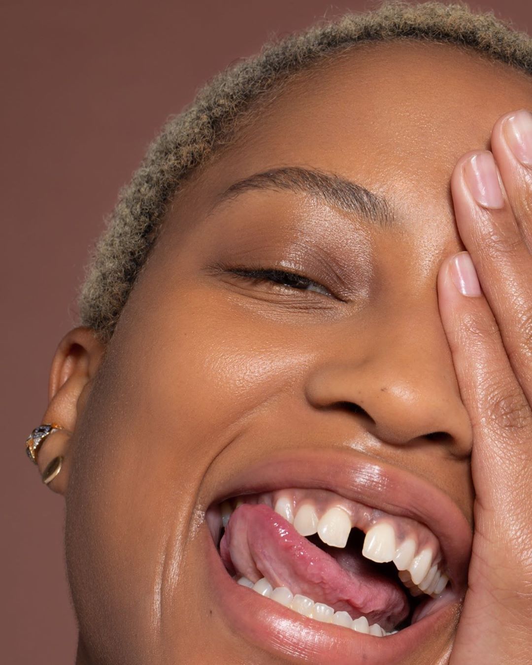 Close-up portrait of a smiling African-American woman with platinum blonde hair, showcasing vibrant and healthy skin in a beauty shot.