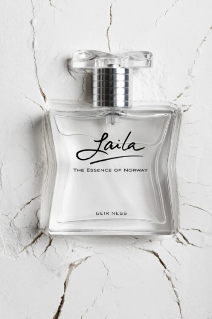 Elegant crystal perfume bottle of Laila, The Essence of Norway, sits on a textured white surface, shot with soft lighting and clarity.