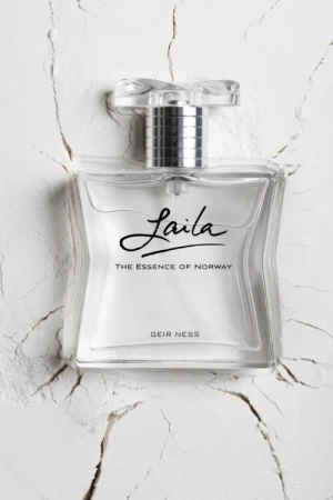 Elegant crystal perfume bottle of Laila, The Essence of Norway, sits on a textured white surface, shot with soft lighting and clarity.