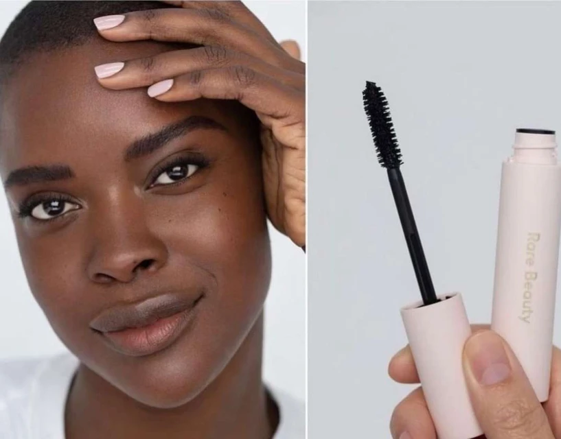 Close-up of an African-American woman holding makeup and a mascara wand. She has short hair and is wearing light pink nail polish.