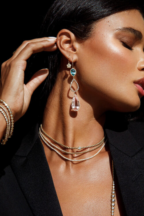 Close-up shot of a brunette woman wearing jewelry: earrings, bracelets, and necklaces in an indoor setting. Beauty and fashion.