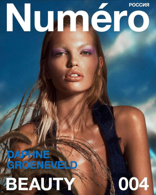 Magazine cover featuring Daphne Groeneveld with blue eyeshadow and glossy skin in front of a bright blue sky and wheat stalks.