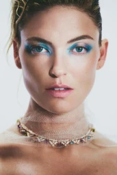 Close-up portrait of a woman with vibrant blue eyeshadow and a jeweled choker necklace by photographers Caleb And Gladys