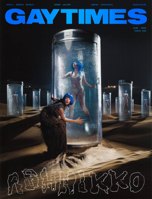 Gay Times magazine cover featuring two women in surreal landscape with cylindrical containers and otherworldly fashion; June 2023 issue.