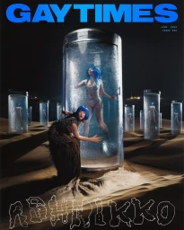 Magazine cover featuring models with blue hair inside vertical glass water cylinders in a desert landscape at night