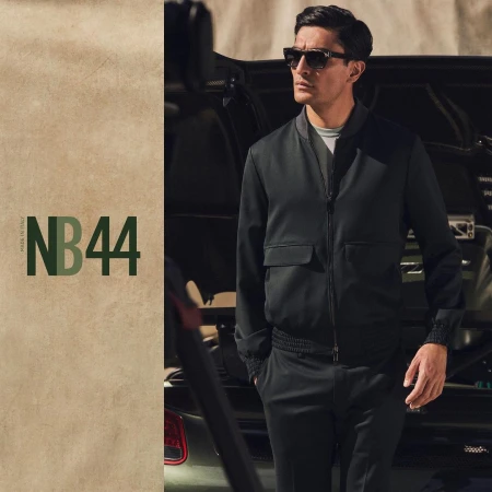 Man wearing dark sunglasses and a black bomber jacket standing in front of a luxury sports car, photographed by Justin Wilczynski.