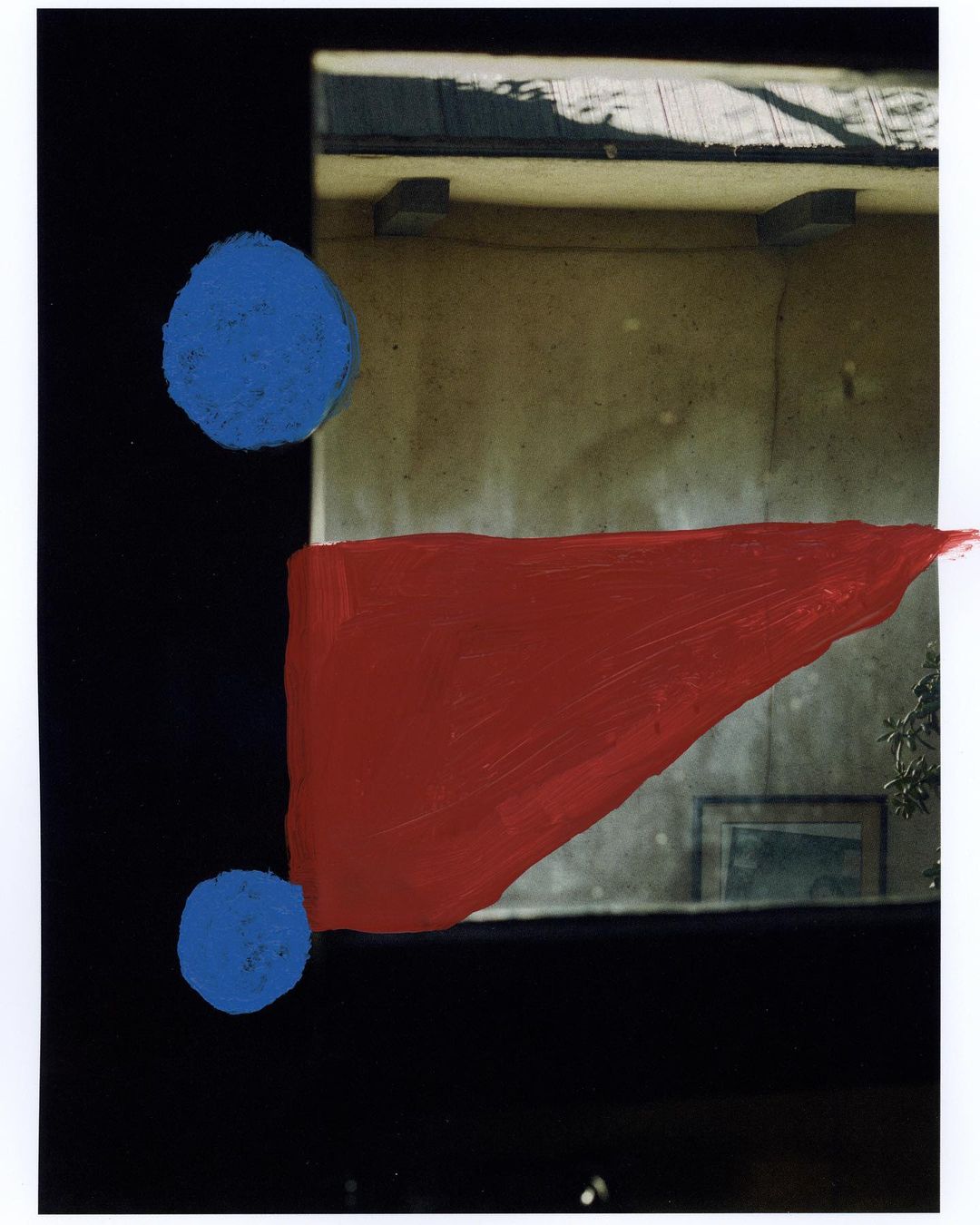 Abstract art featuring geometric shapes, with blue circles and a red triangle against a dark background and building facade.