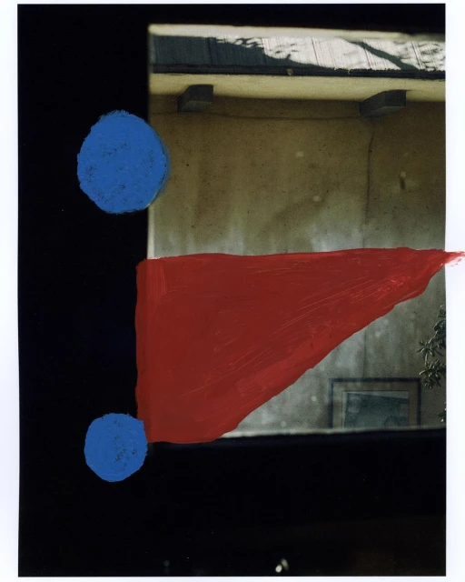 Abstract art featuring geometric shapes, with blue circles and a red triangle against a dark background and building facade.
