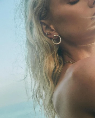 Close-up portrait of a blonde woman wearing a diamond snake hoop earring and an ear cuff, photographed by Justin Wilczynski.