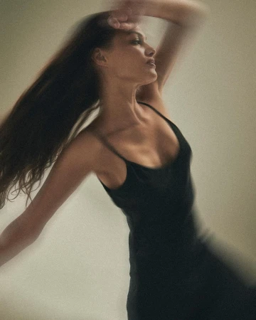 Motion blurred portrait of a woman in a black slip dress with long brown hair by photographer Justin Wilczynski.