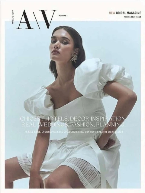 Magazine cover featuring a woman in a white dress with puffed sleeves sitting against a light background, looking directly at the camera.