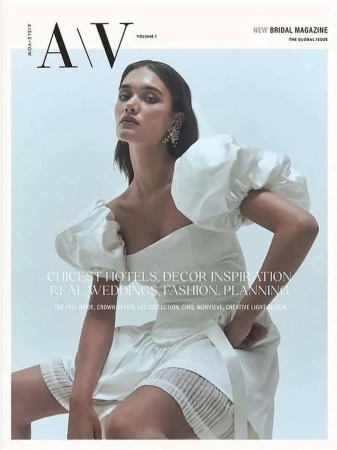 Magazine cover featuring a woman in a white dress with puffed sleeves sitting against a light background, looking directly at the camera.