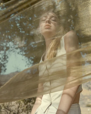 Portrait of a woman viewed through a sheer golden fabric veil outdoors in Los Angeles by Lauren Naylor.