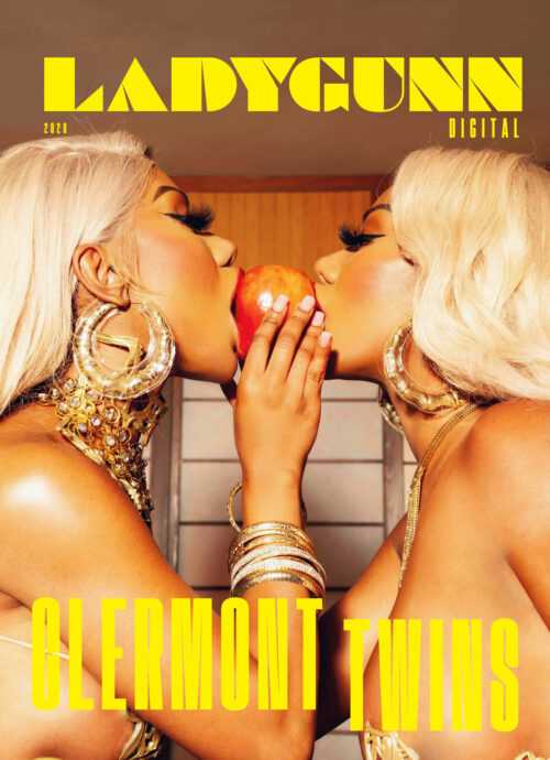 Magazine cover featuring Clermont Twins, two women with blonde hair and elaborate jewelry, sharing an apple in a close-up shot.