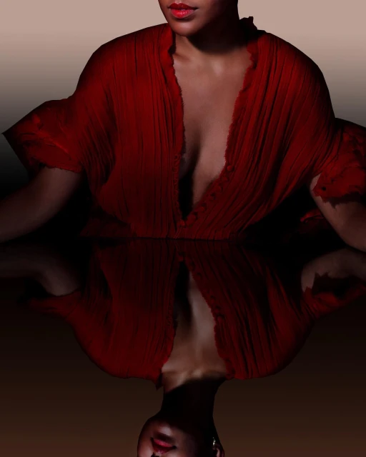 Portrait of woman in red dress with plunging neckline, reflected in dark surface, against a tan background, beauty shot, fashion