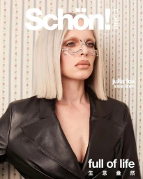 Julia Fox with platinum blonde bob and silver facial jewelry wearing a black leather jacket against patterned wallpaper